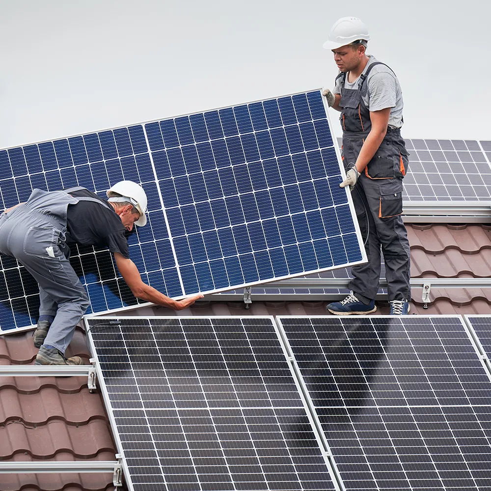 Solar installers fitting photovoltaic panels on a pitched roof in a typical Aylesbury residential property